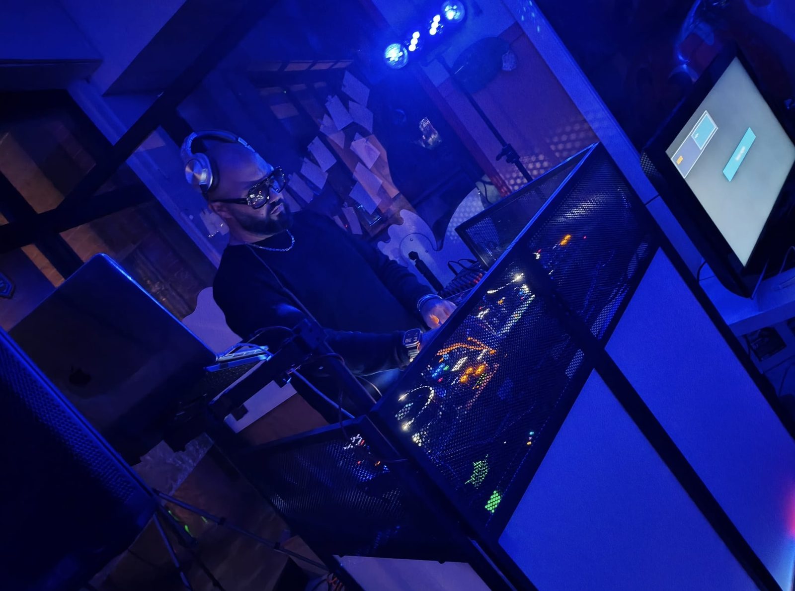 Fabrix DJ alla console in una sala illuminata di blu